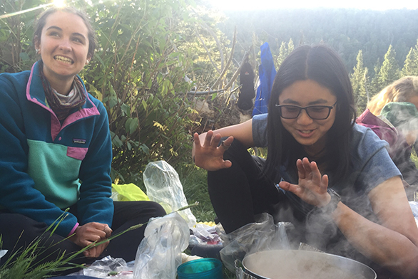 Freshmen Erin Luthin, left, and Bridget Wu smile over a steaming pot.