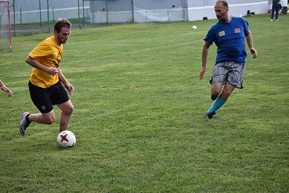 Students and alumni battle in soccer on the upper field.