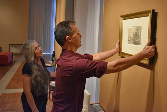 Mitchell Gallery art educator Lucinda Edinberg, left, watches as gallery preparator Neal Falanga begins setting up the exhibit.