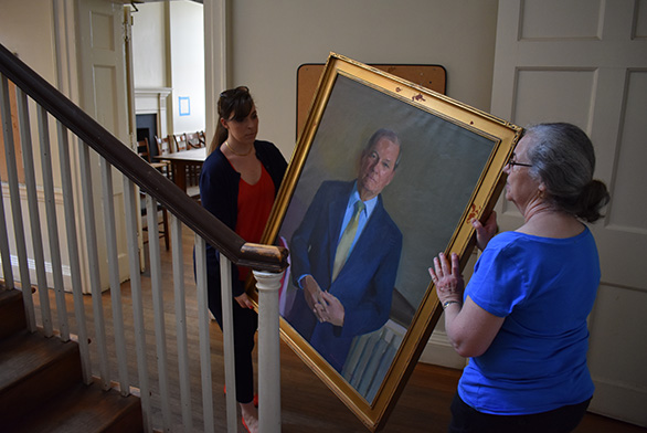 Two women move a painting in McDowell Hall