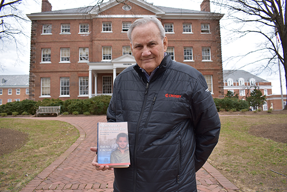 Ralph Crosby holds a copy of his book in front of McDowell Hall.