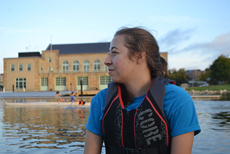 Crew team member Kate Wall rides in the launch boat as her teammates row behind her.