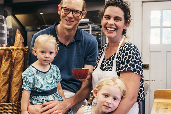 Chris Simmons and Lucy Montgomery share a family moment with their two daughters in their shop's kitchen.